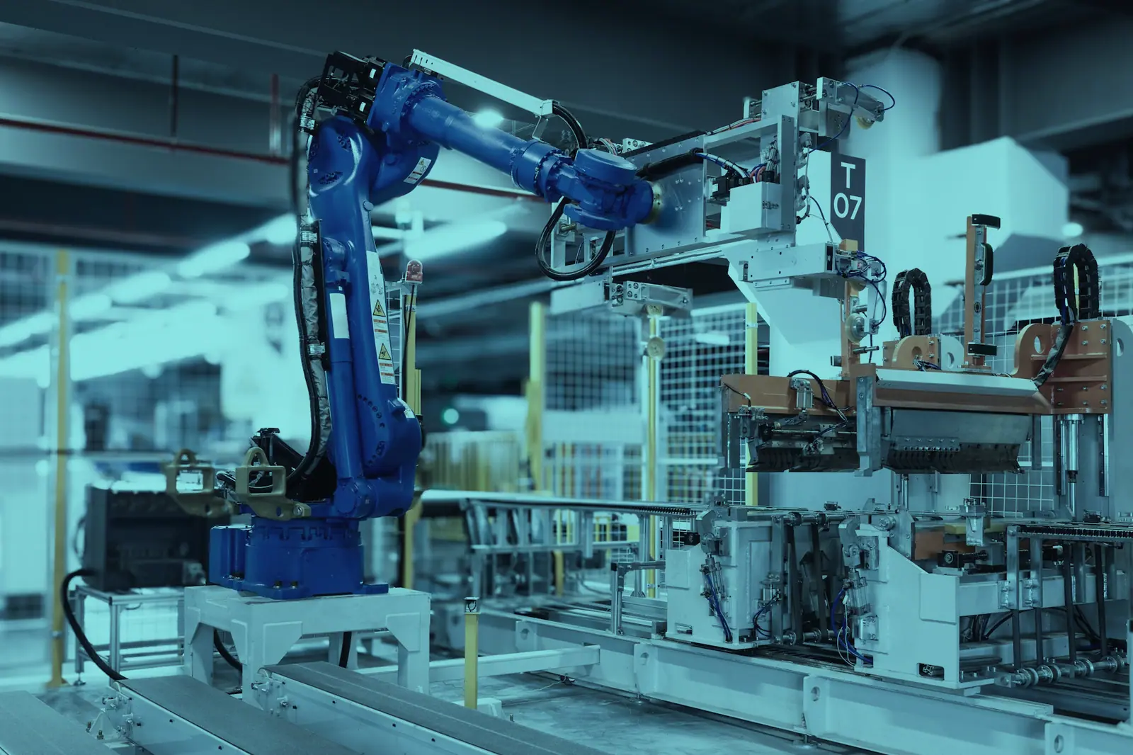 Üretim hattında parça taşıyan mavi gövdeli endüstriyel robot kolu