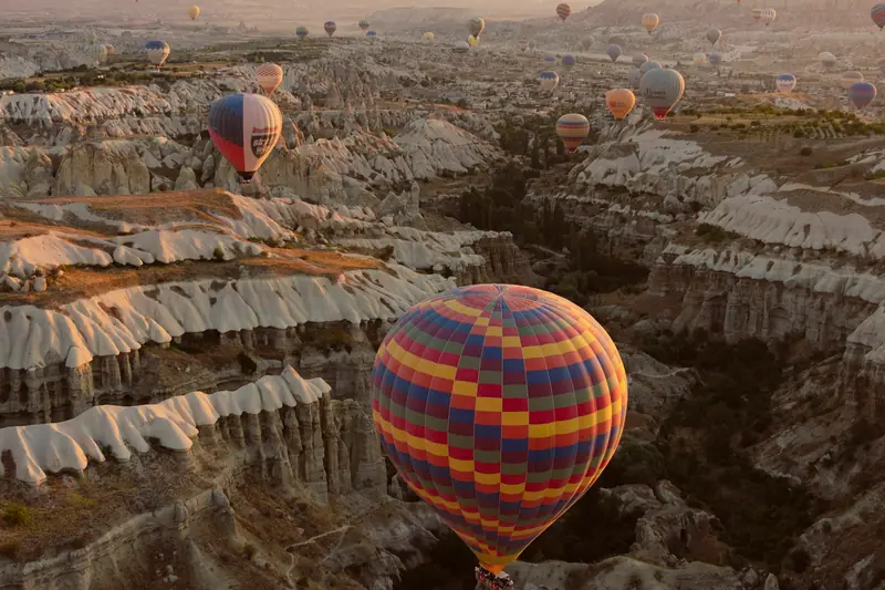 Şafak sökerken vadide şişirilen sıcak hava balonları ve peribacaları